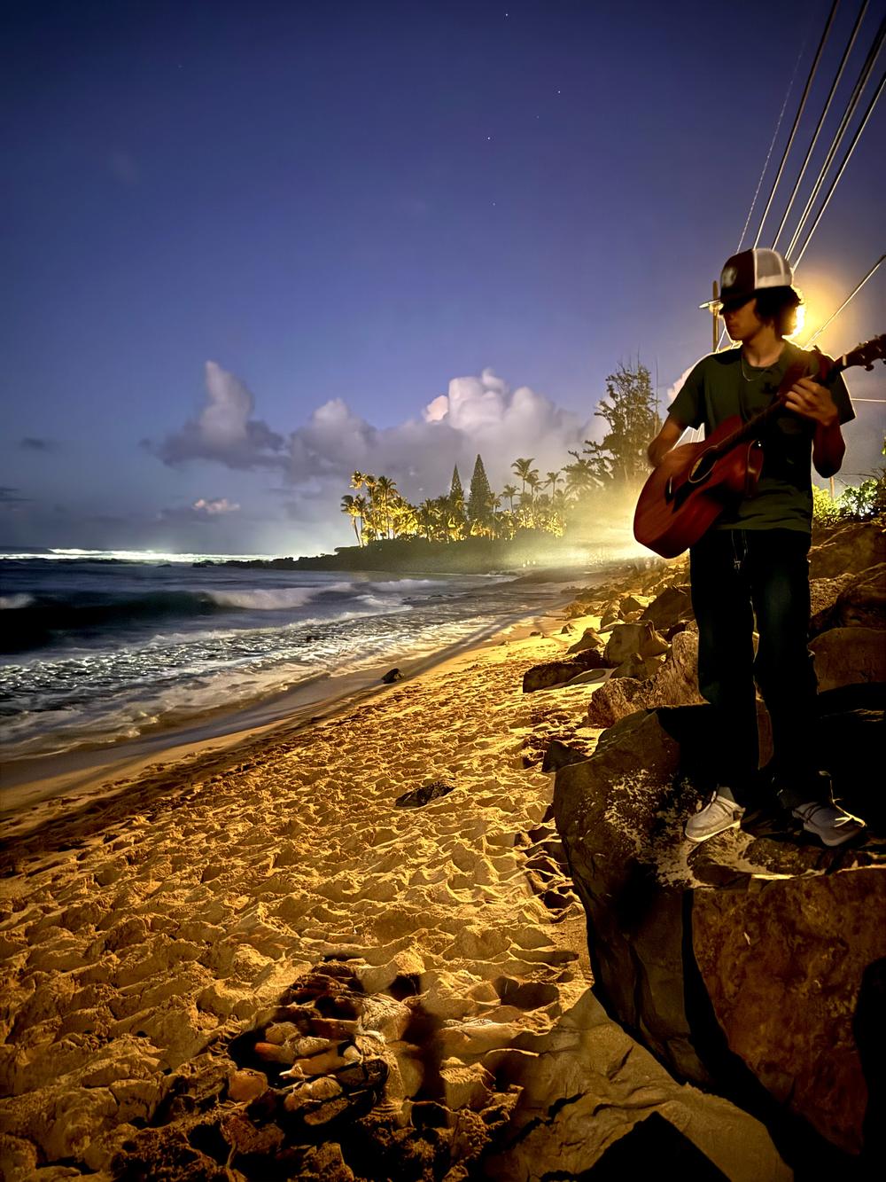 Matteo playing guitar above the beach at dusk