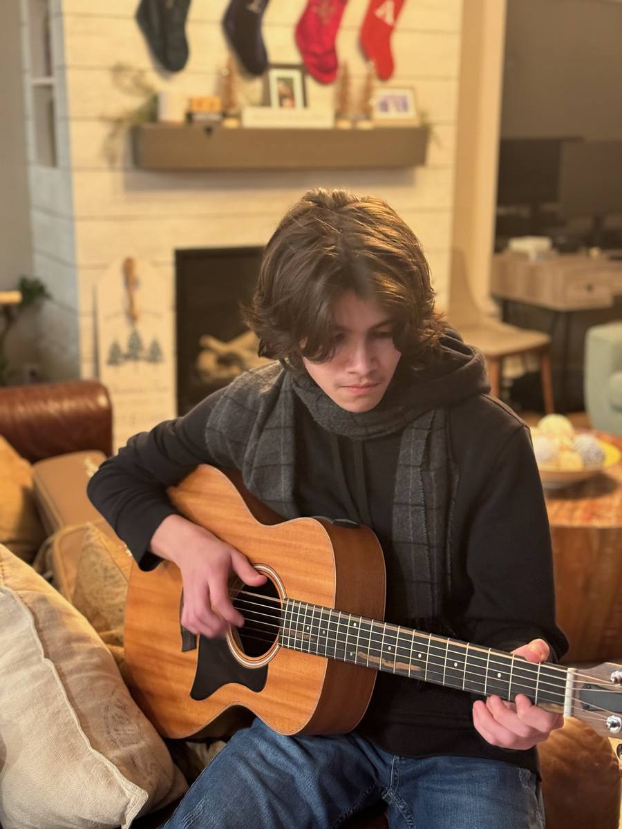 Matteo playing guitar by the fireplace at home